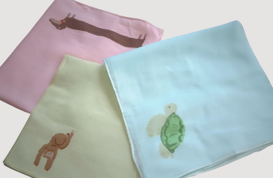 Three colorful baby handkerchief scarfs with designs on a light background